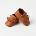 Baby soft-sole leather moccasins in tan brown on white background